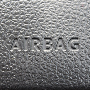 Photo prise de l'intérieur d'une véhicule avec un gros plan sur le nom : "Airbag" présent sur le volant ou le tableau de bord