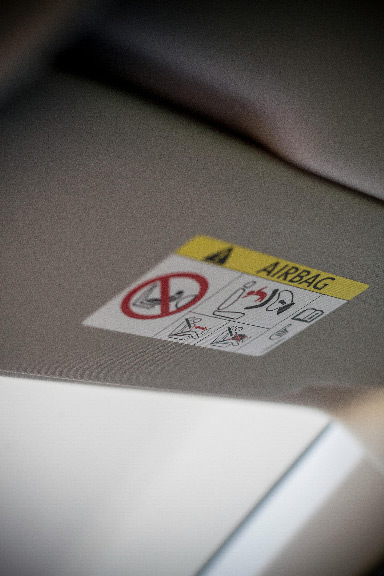 Photo prise de l'intérieur d'une voiture avec un focus sur le par soleil ou on peux lire une étiquette concernant les airbags